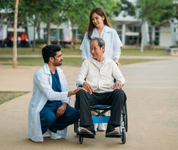 a cancer patient in a wheel chair being pushed by a women and a doctor.